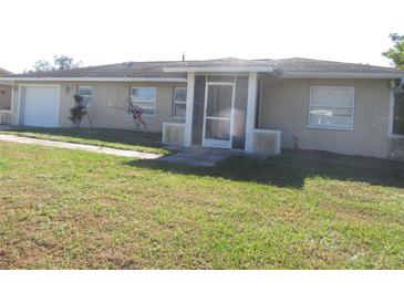 Tan single-story house with a screened porch and attached garage at 21471 Dranson Ave, Port Charlotte, FL 33952