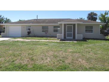 Charming single story home with a simple front yard and an attached garage on a sunny day at 21471 Dranson Ave, Port Charlotte, FL 33952