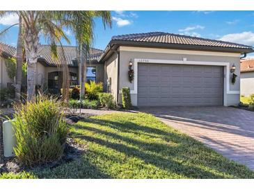 Well-maintained house with gray exterior, a two-car garage, and a landscaped lawn at 12750 Oriago St, Venice, FL 34293