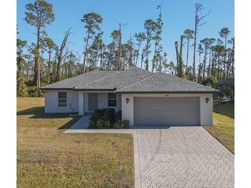 Single-story home with gray roof, paver driveway, and landscaping at 2364 Hagerick Ln, North Port, FL 34288