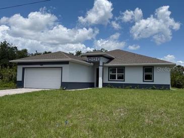 Charming single-story home boasts a two-car garage, neutral paint, and well-manicured lawn against a blue sky at 384 Prineville St, Port Charlotte, FL 33954