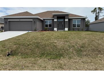 Charming single-story home with a neutral gray facade, well-manicured lawn, and an attached two-car garage at 9159 Melody Cir, Port Charlotte, FL 33981