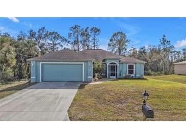 Charming blue home with attached two-car garage and landscaped front yard at 18359 Gypsy Ave, Port Charlotte, FL 33954