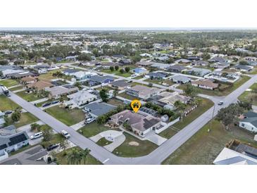 An aerial view of a single Gathering home in a quiet neighborhood featuring mature landscaping and a circular driveway at 23309 Hartley Ave, Port Charlotte, FL 33954