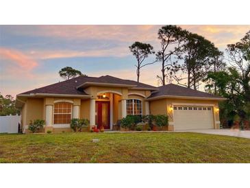 Charming single-story home with a two-car garage and landscaped front yard at sunset at 3100 Sheboygan Ave, North Port, FL 34286