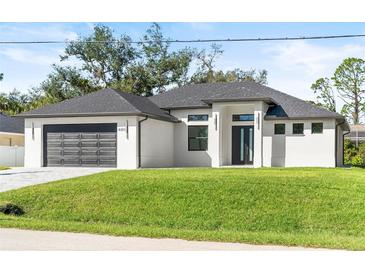 Modern home with a black garage door, impact windows, and a well-manicured lawn showcasing curb appeal at 4301 Marcella Ter, North Port, FL 34286