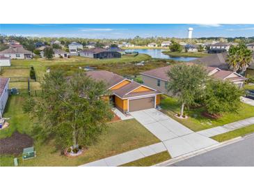 Orange single-story home with two-car garage, landscaped yard, and pond view at 7314 61St E St, Palmetto, FL 34221