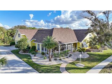 Charming yellow two-story home with a covered front porch and landscaped yard at 1064 Harbour Way Pl, Punta Gorda, FL 33983