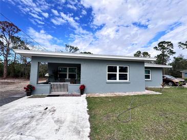 Newly renovated single story home featuring a gray exterior, covered porch, and landscaped yard at 27240 Tribune Blvd, Punta Gorda, FL 33955