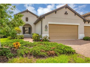 Beige two-story house with a two-car garage and landscaped front yard at 11137 Mcdermott Ct, Englewood, FL 34223