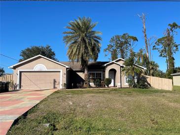 Tan house with palm trees, a garage, and a fenced yard at 4605 Midland St, North Port, FL 34288