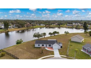 Aerial view of a single-story home on a lake, showcasing a large backyard and neighborhood at 5032 Koli Ct, North Port, FL 34287