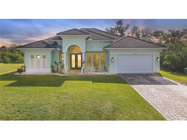 Light green single-story house with tile roof, a fountain, and a two-car garage at 1228 Eppinger Dr, Port Charlotte, FL 33953