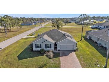 A well-maintained home exhibits appealing curb appeal with a brick driveway and lush lawn in a neighborhood setting at 16031 Alcira Cir, Punta Gorda, FL 33955