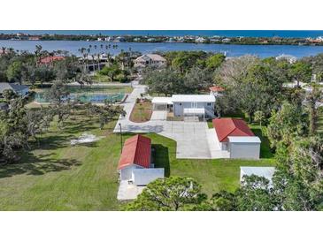 Aerial view of home, detached garages, and tennis court with water views at 1931 Bayshore Dr, Englewood, FL 34223