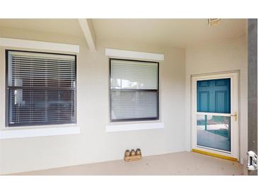 Inviting covered entrance with a blue front door and two adjacent windows with blinds at 2522 Thyme Way, North Port, FL 34289