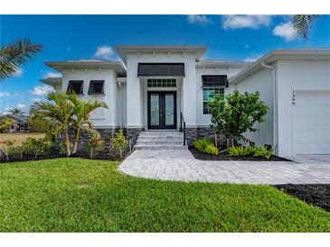 Stunning front exterior showcasing a modern home with lush landscaping and a paver walkway leading to the entrance at 1380 Willet Ct, Punta Gorda, FL 33950