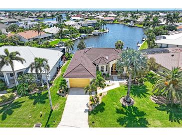 An aerial view of a waterfront home featuring lush landscaping, a tile roof, and canal access at 3663 Whippoorwill Blvd, Punta Gorda, FL 33950