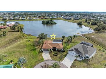 Aerial view of a waterfront property with a screened pool, lush landscaping, and proximity to a tranquil lake at 1115 Venture Ct, Punta Gorda, FL 33983