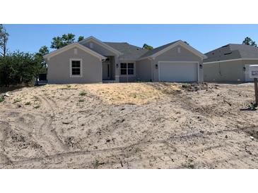 A charming single-Gathering home features a light gray stucco exterior, attached garage, and a neatly landscaped yard at 17439 Edgewater Dr, Port Charlotte, FL 33948