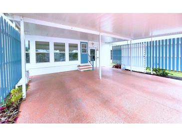 Spacious carport with painted floor and decorative privacy fence and entry to the home at 6642 Acacia Ct, North Port, FL 34287