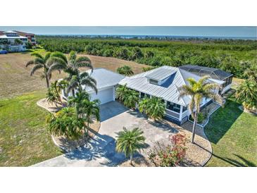 Beautiful single-Gathering home with a metal roof, screened lanai, and tropical landscaping in a coastal setting at 17455 Boca Vista Rd, Punta Gorda, FL 33955