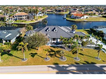 Expansive waterfront home with lush landscaping and a private boat dock, showcasing luxury coastal living at 3415 Tripoli Blvd, Punta Gorda, FL 33950