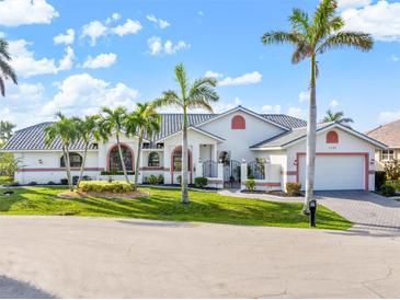 Beautiful single-story home with a tile roof, brick driveway, palm trees, and well-manicured lawn at 1105 Rum Cay Ct, Punta Gorda, FL 33950