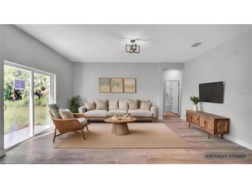 Bright, neutral living room featuring a comfortable sofa, stylish decor, and sliding glass doors at 1117 Vernon Ave, Port Charlotte, FL 33948