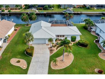 Beautiful home featuring a metal roof, lush landscaping, and a waterfront view with canal access at 1118 Treasure Cay Ct, Punta Gorda, FL 33950