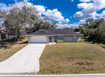 Charming one-story home featuring an attached two-car garage and a long driveway on a sunny day at 1018 Presque Isle Dr, Port Charlotte, FL 33952