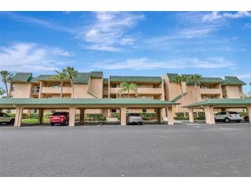 Condo building with covered parking featuring palm trees under a sunny blue sky at 601 Shreve St # 13A, Punta Gorda, FL 33950