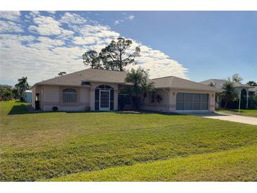 Charming single-story home with a well-maintained lawn and mature landscaping at 23395 Mullins Ave, Port Charlotte, FL 33954