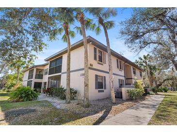 Exterior view of a two-story condo with palm trees and manicured landscaping at 19505 Quesada Ave # Ss102, Port Charlotte, FL 33948