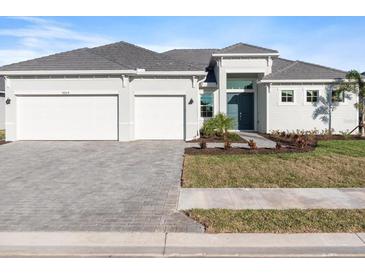 Beautiful single-story home with a three-car garage and gray brick driveway at 8604 Shore Lake Dr, Englewood, FL 34224
