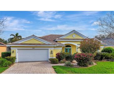 Charming one-story home with a yellow exterior, tile roof, a brick driveway, and meticulously maintained landscaping at 1616 Palmetto Palm Way, North Port, FL 34288