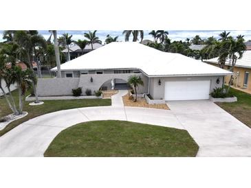 Inviting single-story home featuring a circular driveway, well-manicured lawn, and arched entryway at 931 Bal Harbor Blvd, Punta Gorda, FL 33950