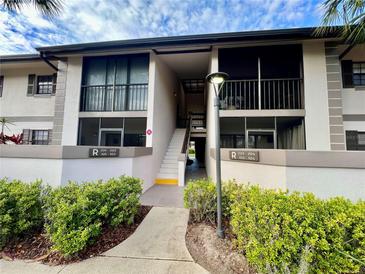 Condo exterior showing the units above on the second floor with screened balconies and stairs in the center at 1515 Forrest Nelson Blvd # R201, Port Charlotte, FL 33952