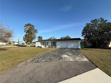 Single story home with an attached two car garage and a driveway that needs some TLC at 690 Ennis Nw Ter, Port Charlotte, FL 33952