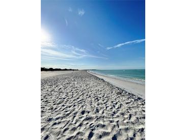Expansive white sand beach with clear turquoise water and a bright blue sky backdrop at 9400 Little Gasparilla Is # C2, Placida, FL 33946