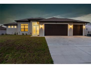 Charming single-story home featuring a spacious three-car garage and well-manicured lawn, illuminated for evening appeal at 23218 Fawn Ave, Punta Gorda, FL 33980