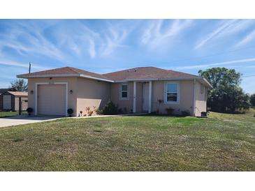 Charming single-story home with a well-maintained lawn and attached garage is bathed in sunlight under a blue sky at 30035 Alder Rd, Punta Gorda, FL 33982