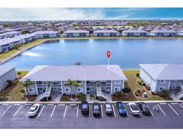 An aerial view of the condominium building with its manicured lawns, lakeside position, and ample parking at 3310 Loveland Blvd # 1808, Punta Gorda, FL 33980