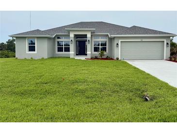 Inviting single-story home featuring a well-manicured lawn and a two-car garage at 9171 Waldrep St, Port Charlotte, FL 33981