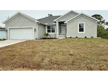 Charming single-story home featuring a two-car garage, manicured landscaping, and a welcoming front porch at 9590 Little Rock St, Port Charlotte, FL 33981