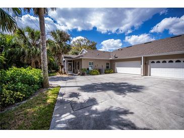 Spacious driveway leads to a charming home with an attached garage and lush, tropical landscaping at 1355 Red Oak Ln, Port Charlotte, FL 33948