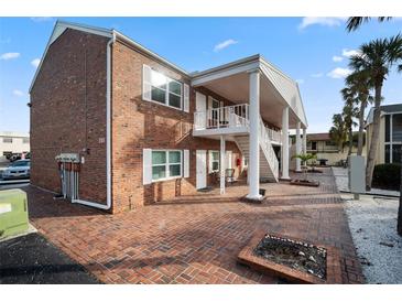 Two-story brick exterior with white trim, staircase and red brick entryway and courtyard at 380 Base E Ave # 202, Venice, FL 34285