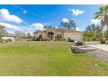 Charming single-story home with a manicured lawn and lush landscaping under a bright blue sky at 3816 N Cranberry Blvd, North Port, FL 34286