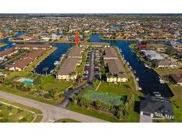 Stunning aerial view of a waterfront condo community with boat docks and a tennis court at 4000 Bal Harbor Blvd # 227, Punta Gorda, FL 33950