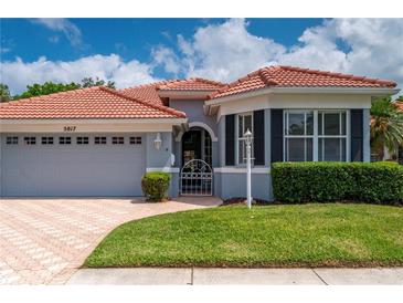 Charming home exterior featuring a terracotta roof, lush greenery, and a brick paved driveway at 5017 Hanging Moss Ln, Sarasota, FL 34238
